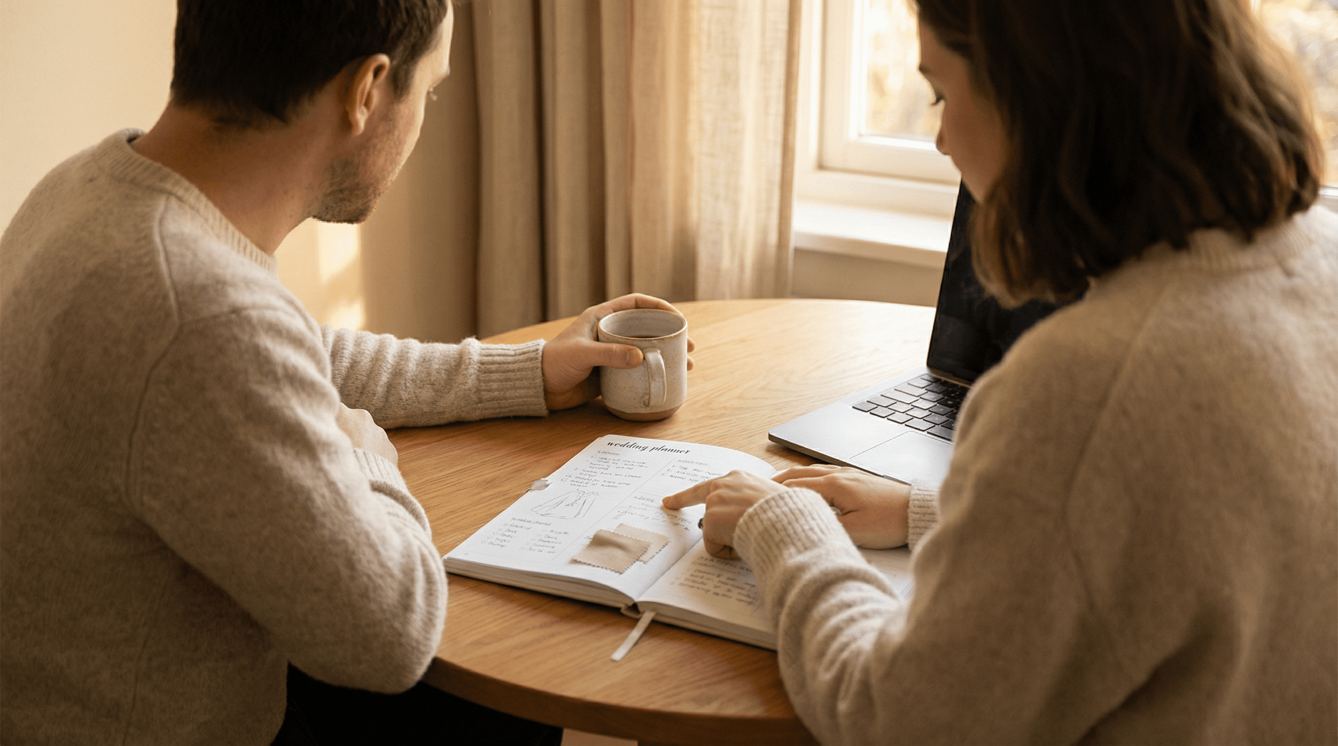 Brautpaar plant gemeinsam die Hochzeit mit Notizbuch und Laptop